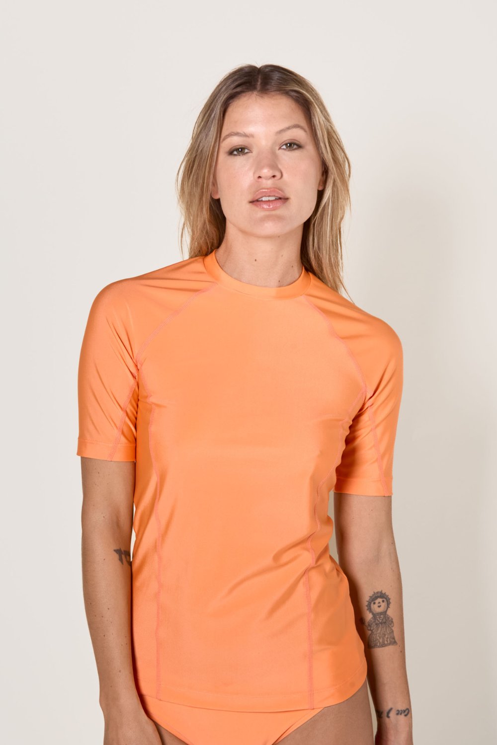 T-shirt anti-UV orange pour femme, coupe ajustée et respirante, certifié UPF 50+, idéal pour les activités aquatiques.